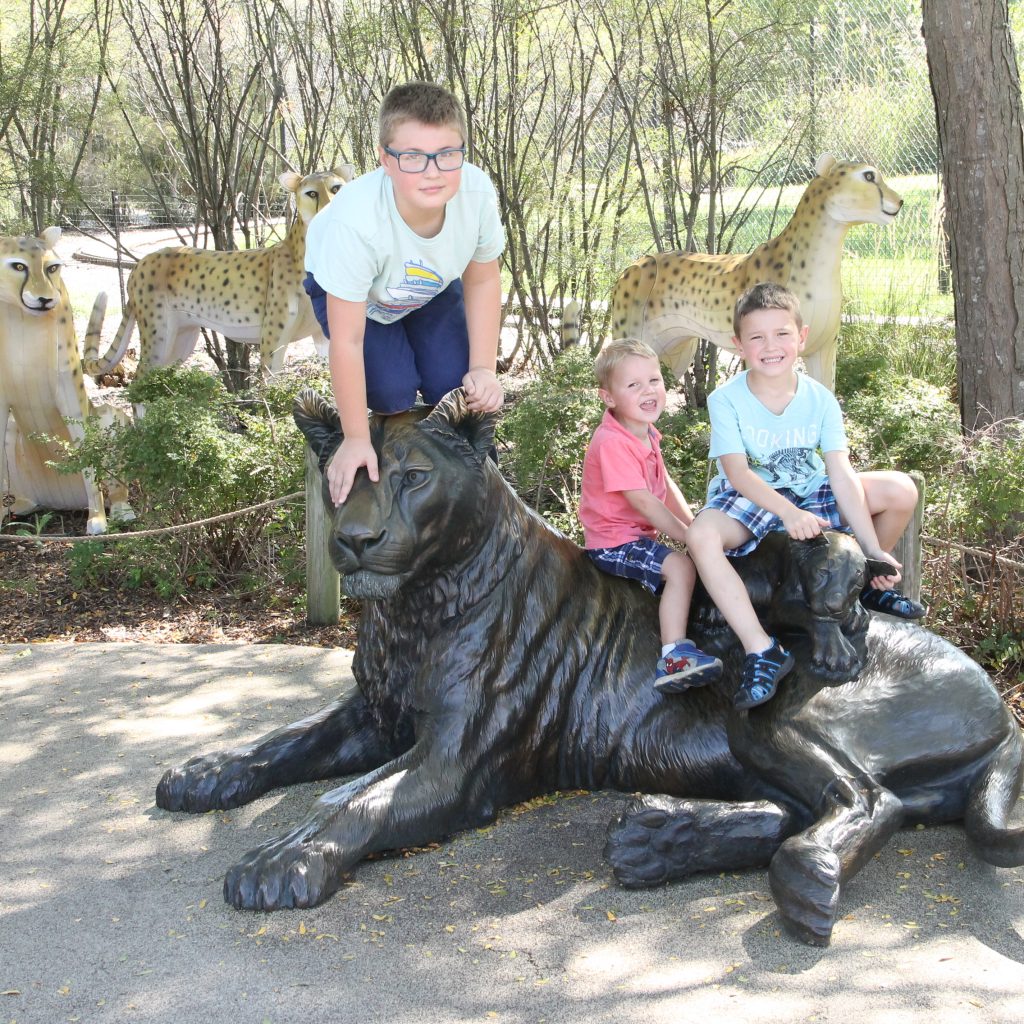 Boys posing with a tiger statue at the zoo