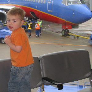 How to budget vacation flights.  Boy looking at airplane out window