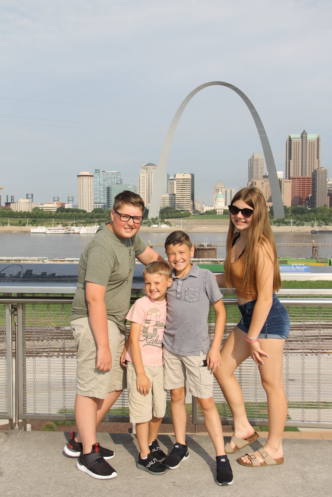 Kids posing in front of the Gateway Arch whiile checking out unique road trip stops in the midwest