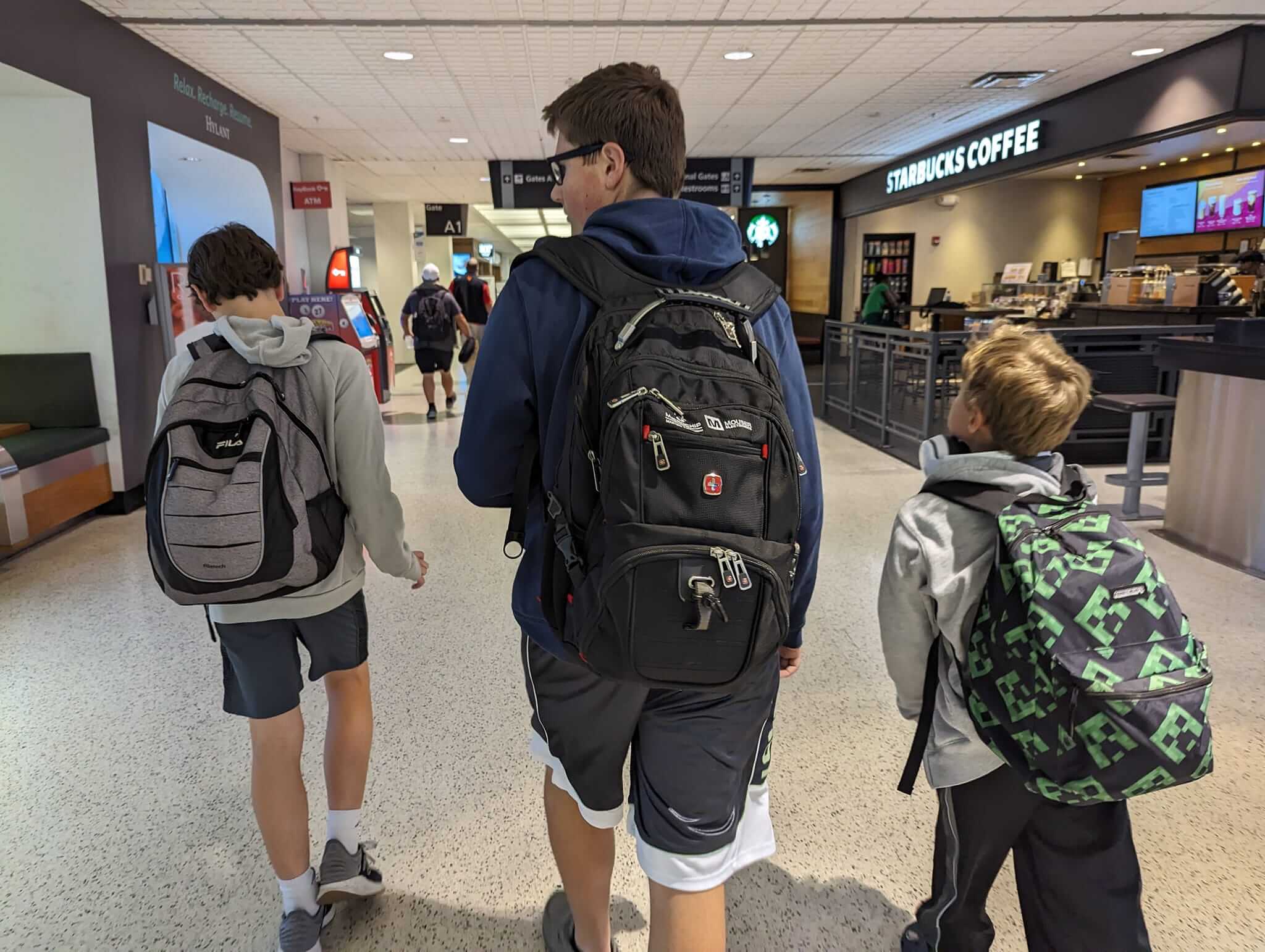 Kids carrying their bookbags, which are free personal items for flights, rather than checking bags