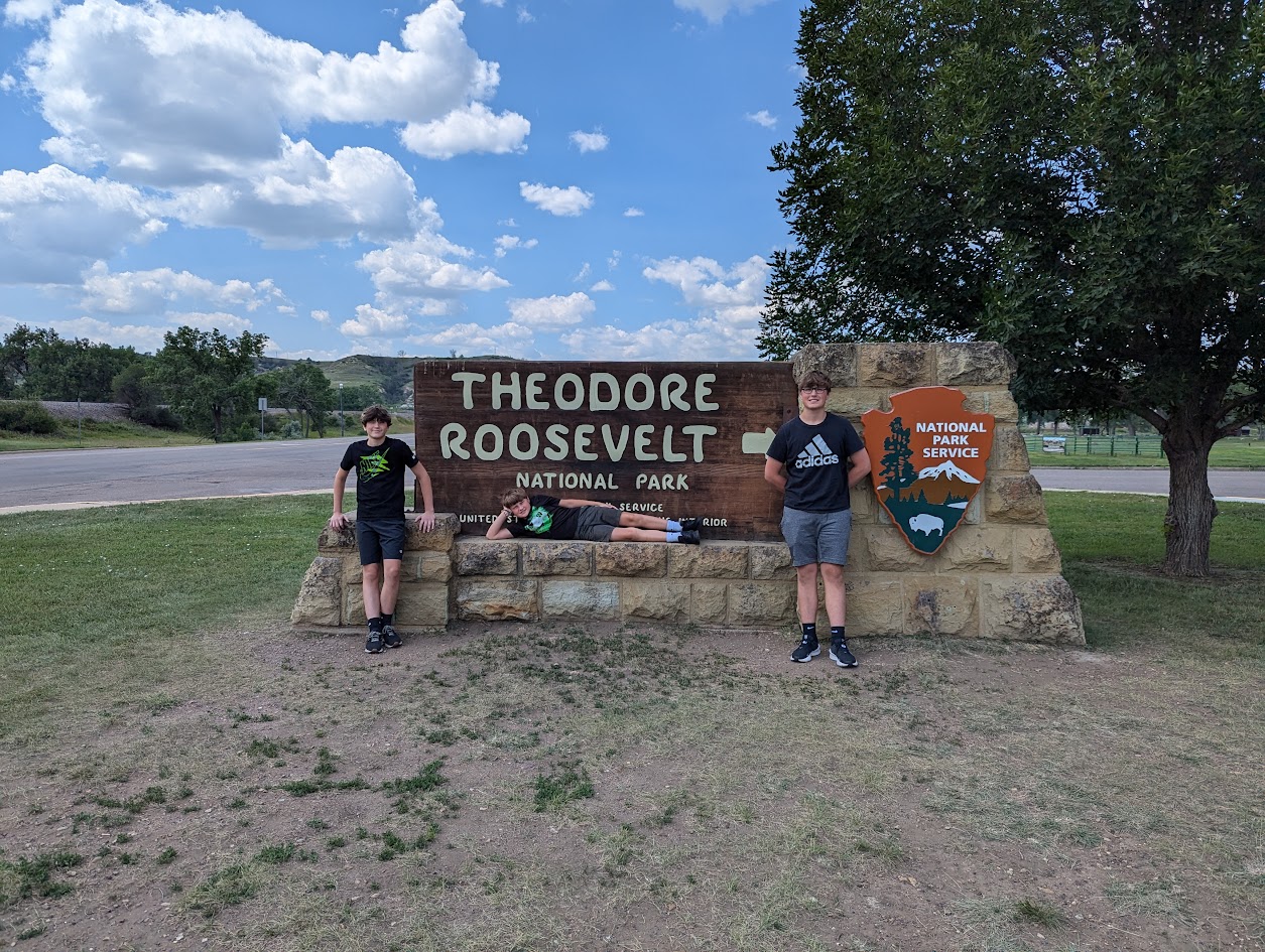 Boys at the entrance sign to Theodore Roosevelt National Park